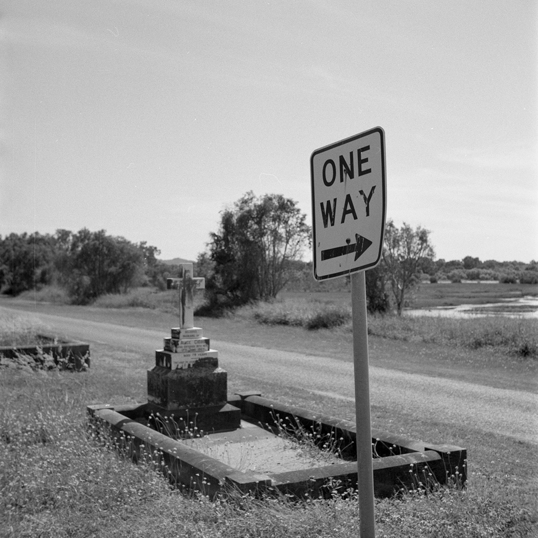 A grave with a one way sign in front of it.